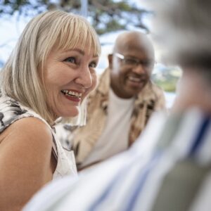 Happy senior woman socializing and chatting with friends at a restaurant table on the weekend
