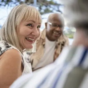 Happy senior woman socializing and chatting with friends at a restaurant table on the weekend