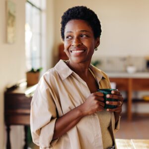 happy black woman smiling with cup of coffee at home