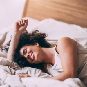 curly haired woman laughing on bed